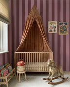 Brede Strepen Bordeaux Roze – Atelier Chien: behang in een kinderkamer met wieg en hemeltje.