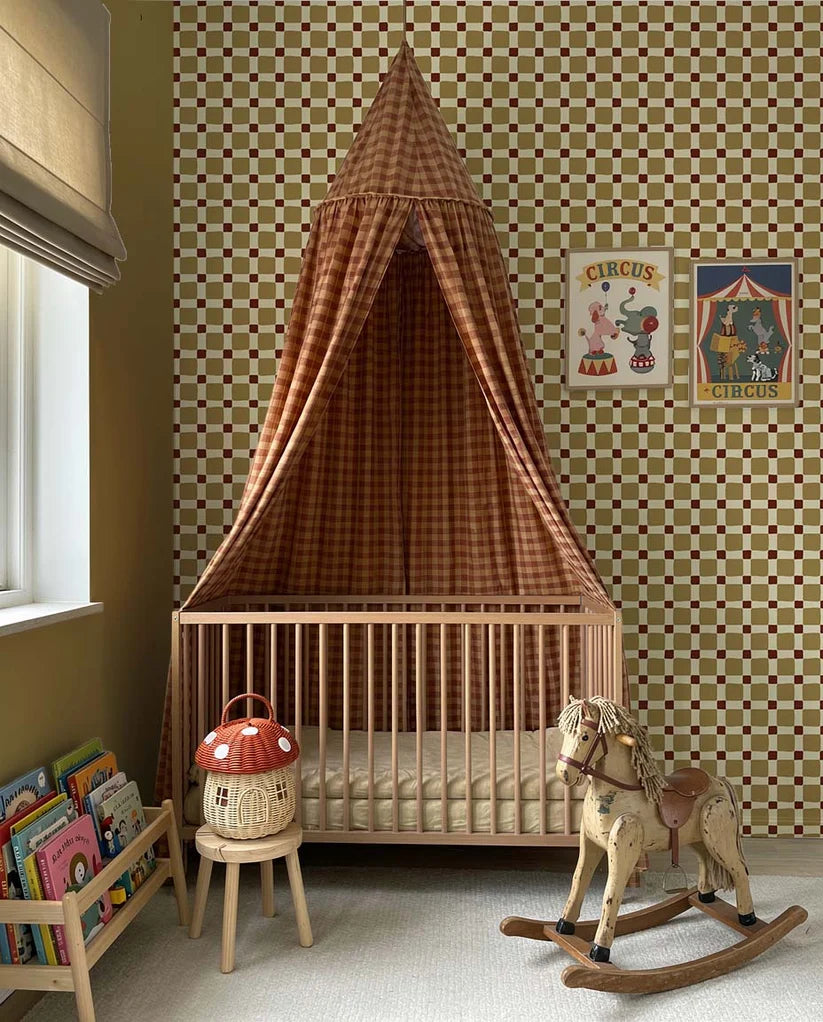 Geblokt Quilt Olijfgroen – Atelier Chien: behang achter een wieg met hemeltje en hobbelpaard.