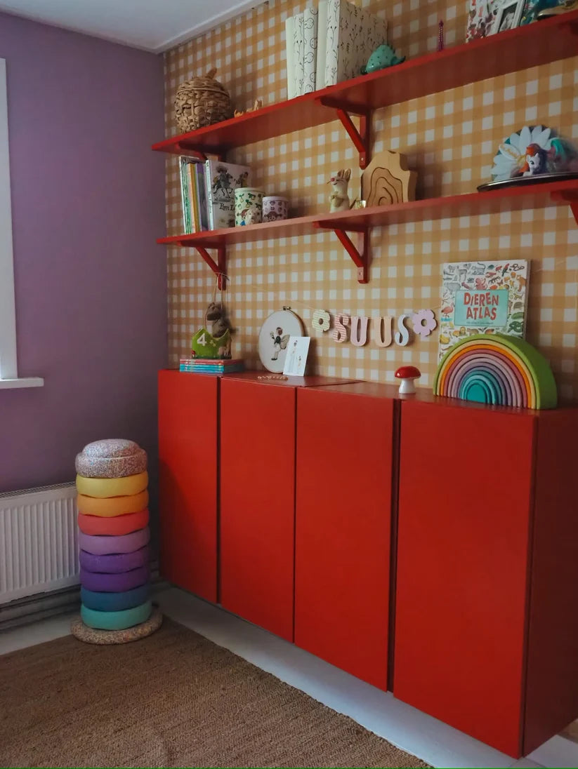 Okergeel ginghambehang van Atelier Chien achter een rode kast en wandplanken.