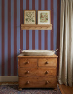 Brede Strepen Bordeaux Blauw – Atelier Chien: Tapete hinter einer Holzkommode mit Wickelkorb.
