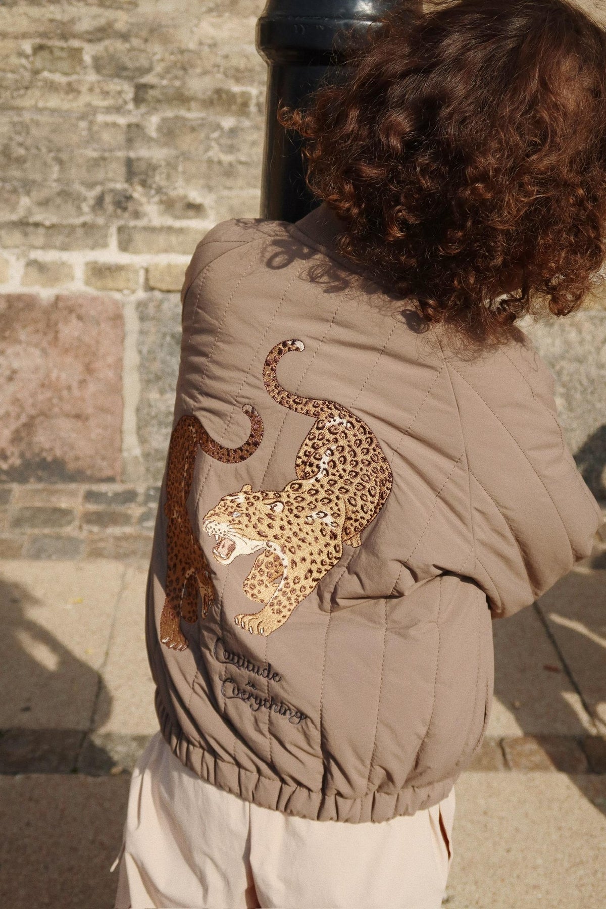 Thermojacke Juno Bomber – Walnut – Konges Sløjd: Detail der Leoparden-Illustration auf der Rückseite der getragenen Bomberjacke.