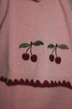 Wollen vest Collette – Pale Blush – Konges Sløjd: detail van de geborduurde kersen en onderrand van het roze vest.