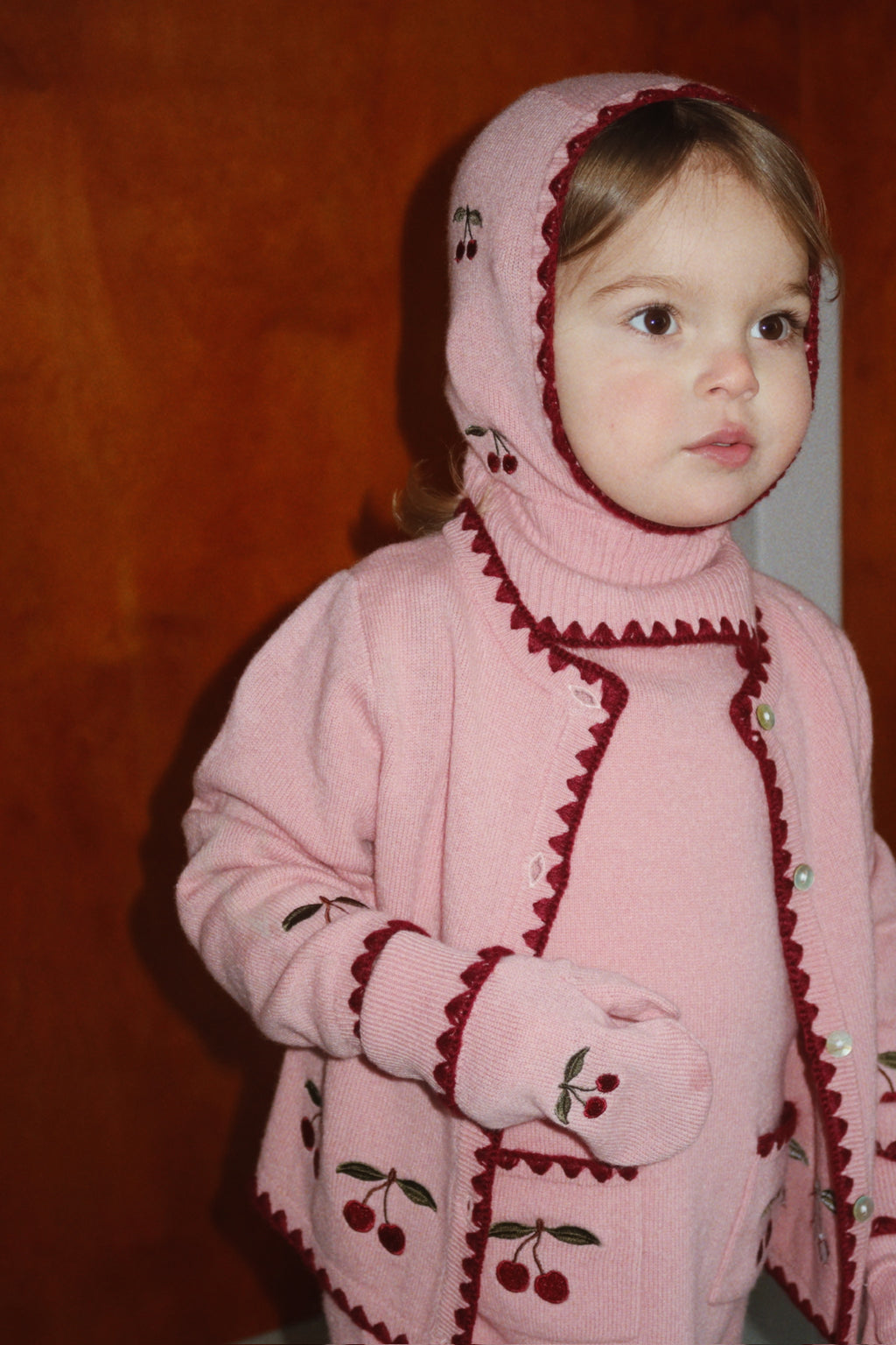 Wollen vest Collette – Pale Blush – Konges Sløjd: kind met roze vest en bijpassende kersenbalaclava.